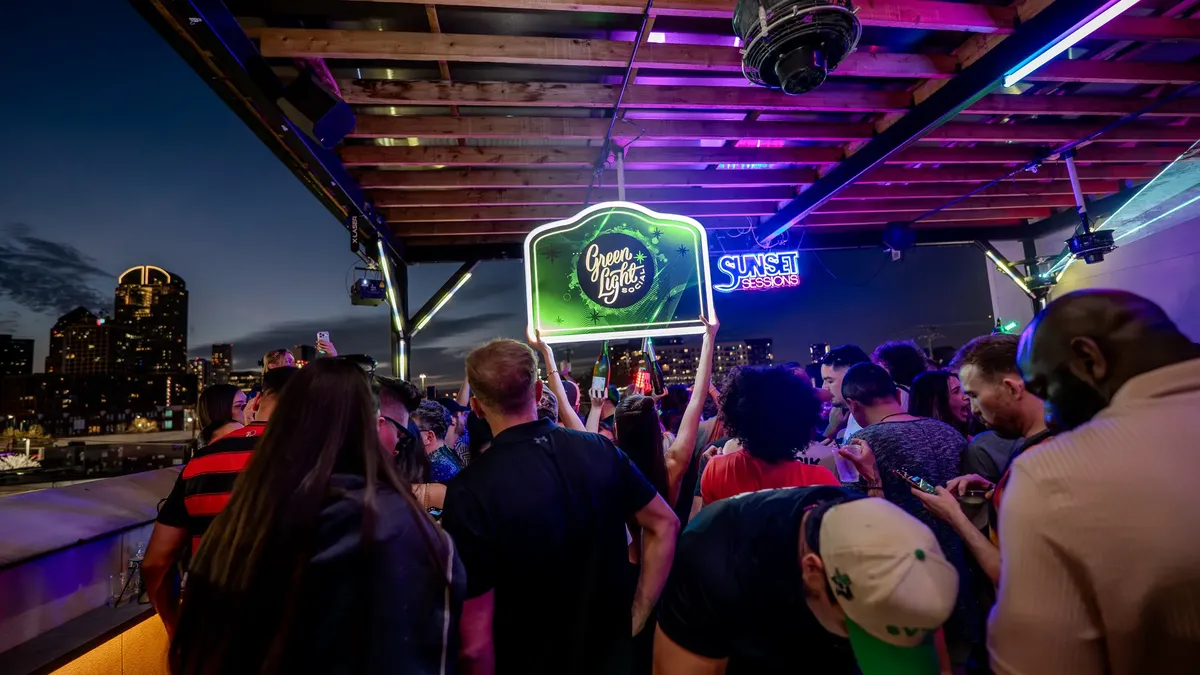 Packed rooftop at Sunset Sessions with Dallas skyline